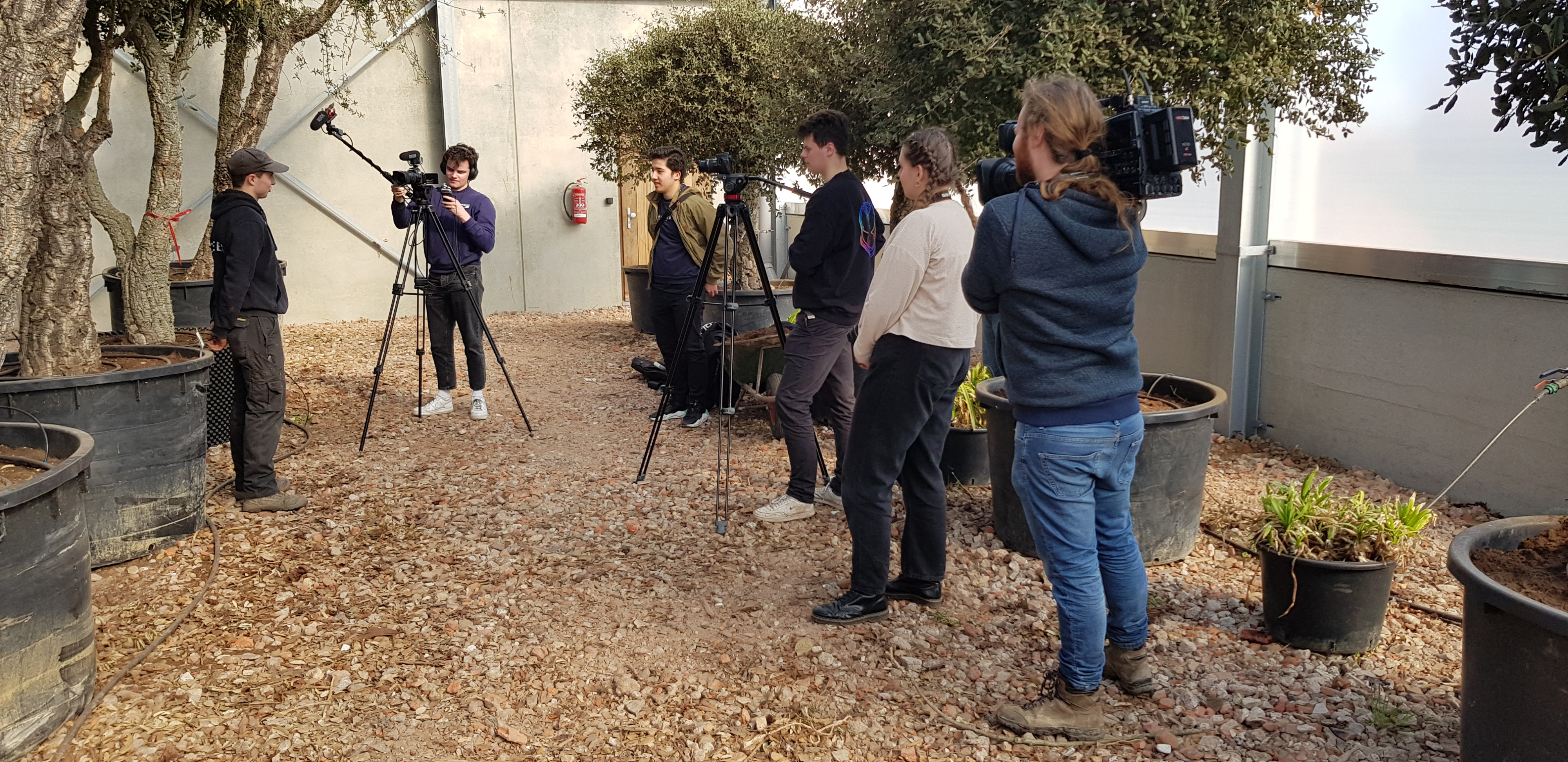 een cameraploeg interviewt een jongere in een kwekerij